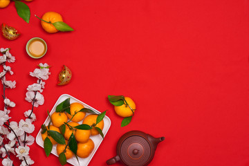 Top view accessories Chinese new year festival decorations.orange,leaf,wood basket,red packet,plum blossom on red background.
