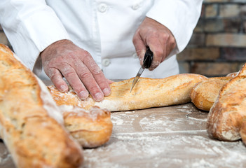 baker cutting traditional bread french baguettes