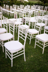 File di sedie bianche allineate e tappeto passatoia bianco sul prato addobbato con composizioni floreali per un matrimonio 