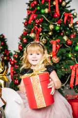 mother with daughter sitting near christmas tree and opening gifts