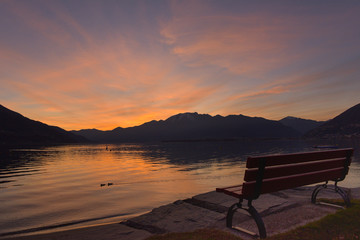 Fototapeta na wymiar Panchina al molo durante un tramonto serale con cielo colorato di blu, rosa e giallo