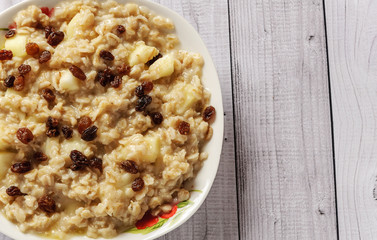 Oatmeal with apple and raisins against the background of the old tree. Muesli with an apple and raisins