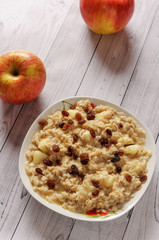 Oatmeal with apple and raisins against the background of the old tree. Muesli with an apple and raisins