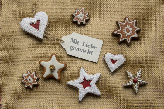 MIT LIEBE GEMACHT Schrift auf Schildchen Pl&auml;tzchen Herzen und Sterne Hintergrund aus Jute