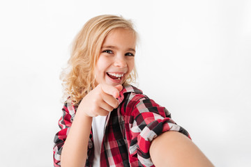 Portrait of a cheery little girl pointing finger at camera