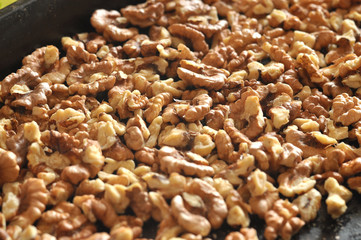 Baked walnut kernels on a black backing tray close-up. Walnut background.