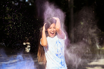 Laughing young asian woman with long hair playing with Holi purple paint