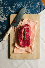 Steak on wooden chopping board with Damascus steel knife