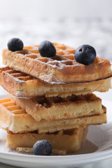 Waffles on a white plate decorated with blueberries with marbled background. copy space