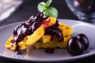 Waffles with cherry jam and mint leaves
