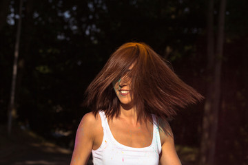 Joyful young woman with wind in hair celebrating Holi Festival