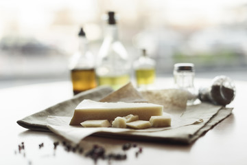 selective focus of piece of cheese on napkin and oil in bottles