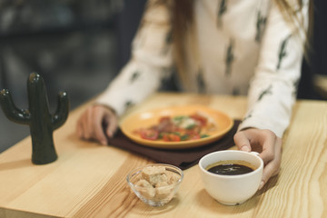 selective focus of woman sitting at table with cup of coffee and pizza piece on plate