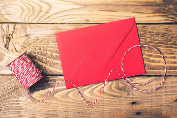 Red and white rope roll and red envelope on a wooden table. Top view.