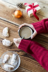 girl holding cup of coffee on wooden table with christmas decoration 