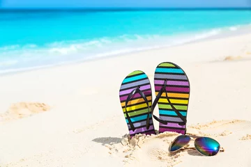 Küchenrückwand glas motiv Ozeanien Mehrfarbige Flip-Flops und Sonnenbrillen an einem sonnigen Strand. Tropisches Strandurlaubs- und Reisekonzept.