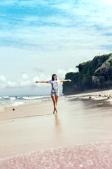 Fototapeta na wymiar Beautiful young woman in sunglasses posing on the beach of a tropical island of Bali, Indonesia.