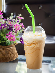 Coffee blend in plastic cup. Served with whipped cream topping and sweet syrup. Favorite caffeine beverage. Dark vignette with cafe view