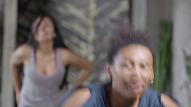 Medium shot of energetic African woman laughing and dancing in zumba class