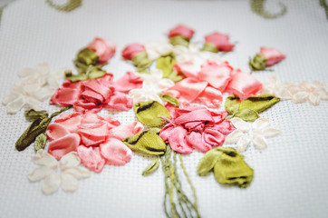 Beautiful flowers embroidered ribbon. Needlework, handicraft. Close-up, selective focus.