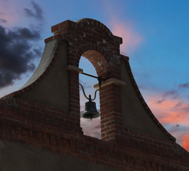 A Brick and Stucco Bell Tower in a Sunset Sky