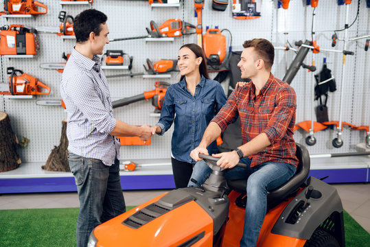 A consultant in a garden tools store shows a customer a lawn mower.
