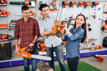 The seller in the store shows the customers a chainsaw.