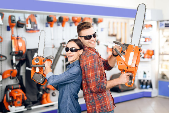 A guy and a girl are posing on the camera with chainsaws in their hands.