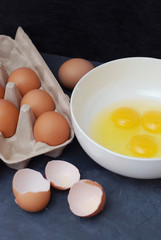 Raw Eggs in Bowl on Kitchen Table. Preparation of Omelet. Dark Blue Background.