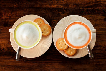 The couple cups with colorful Thai milk tea on the brown wooden background, top view.