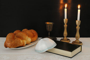 shabbat image. challah bread, shabbat wine and candles on the table.