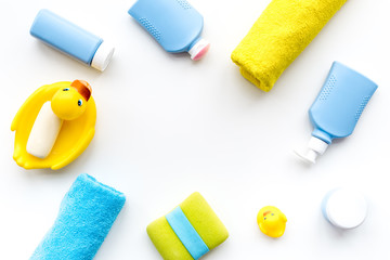 Bath accessories for kids. Yellow rubber duck, soap, sponge, brushes, towel on white background top view copyspace