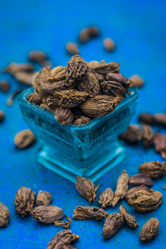 Raw black cardamom on a brownish wooden surface.
