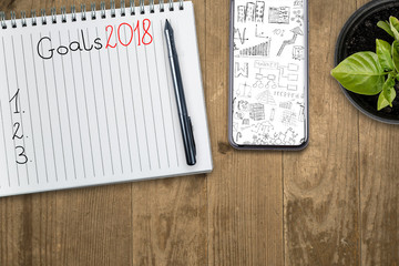 Goals in 2018. View from the top of the flat lying objects on the table and in the notebook recorded goals for 2018.