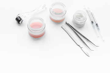 Dermatologist or cosmetologist accessories. Dermaroller, creams and mask, beauty injection, tools on white background copyspace