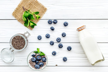 Eat chia seeds for breakfast with yogurt, blueberry and mint. White wooden background top view