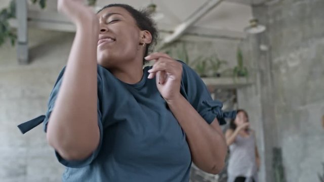 Medium shot of ecstatic African woman dancing zumba in group class