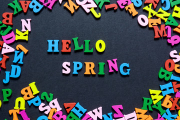 concept design - the word HELLO on SPRING from multi-colored wooden letters on a black background, creative idea.
