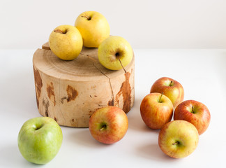 Colorful apples on white table and on wooden stump.