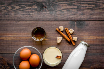 Make eggnog classic recipe. Eggs, milk, cinnamon, whiskey on dark wooden background top view copyspace