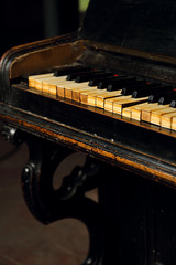 Old vintage classical black piano in dramatic light on dark background. Closeup