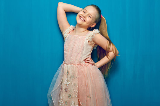 Smiling kid girl with long blond hair wearing pink dress