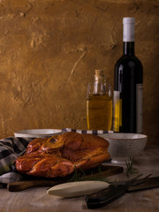 Smoked pork meat on cutting board with kitchen utensils and wine