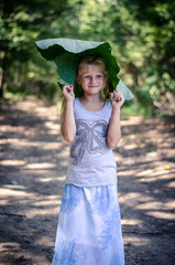 little lovely girl holding a green burdock over her head