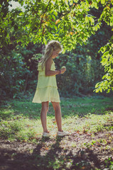 little lovely girl in yellow dress standing under the tree