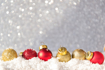 Christmas glitter balls placed on snow and silver background