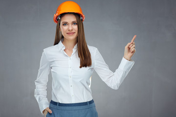 Smiling businesswoman wearing builder helmet pointing finger