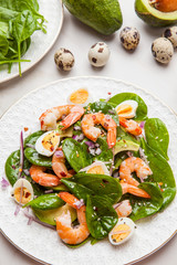 Fresh, healthy salad with shrimps, spinach and avocado on a marble table