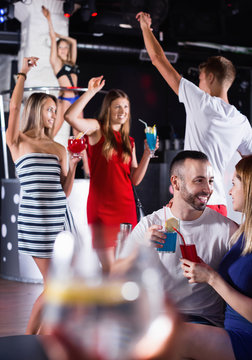 Female and male clubbing with cocktail in the club on party