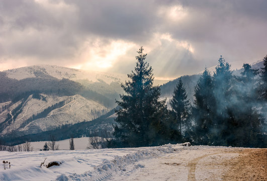 stormy winter sky over spruce forest in fog by the road at the mountain hill